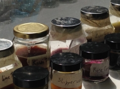 An image of nine recycled jars with handwritten labels filled with homemade inks.